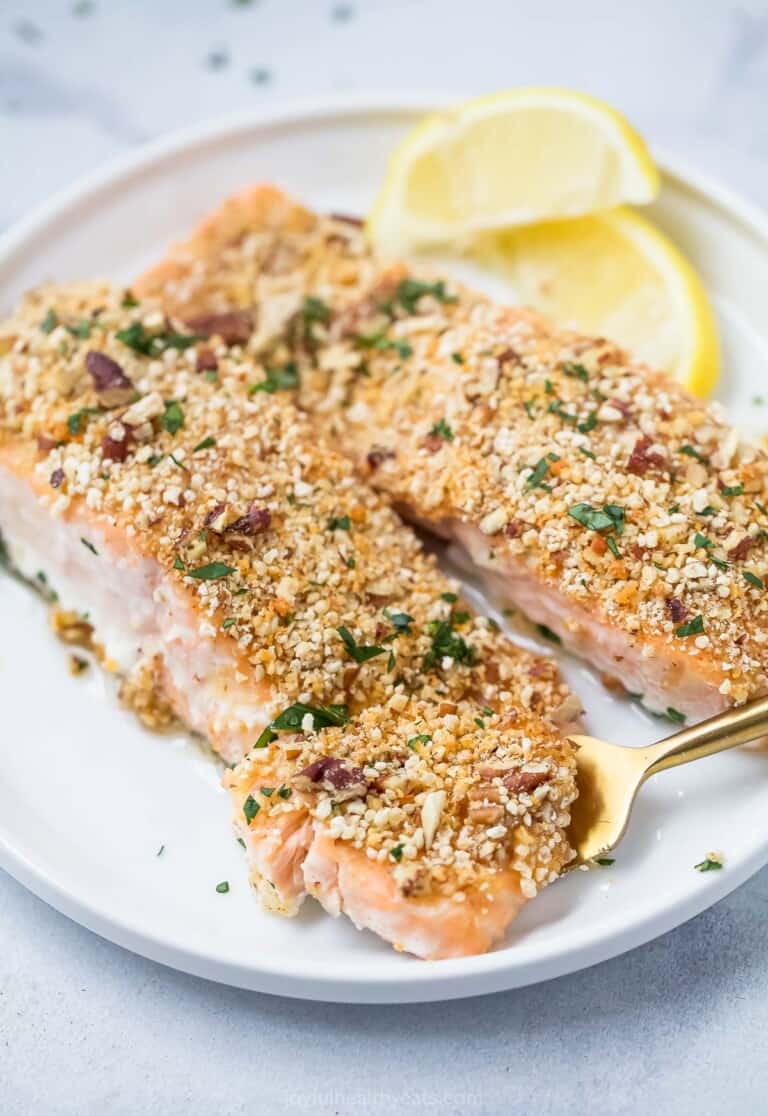 Pecan crusted salmon with lemon wedges on the side.