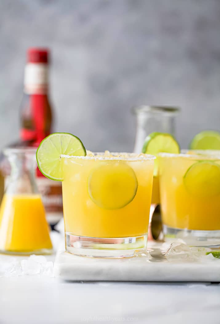 Glasses filled with margaritas and topped with lime wedges