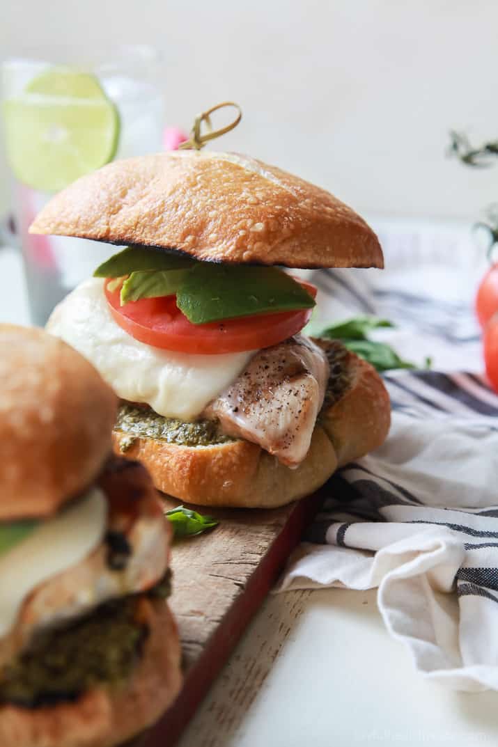 Close up of two Grilled Avocado Caprese Chicken Sandwiches on a wooden board