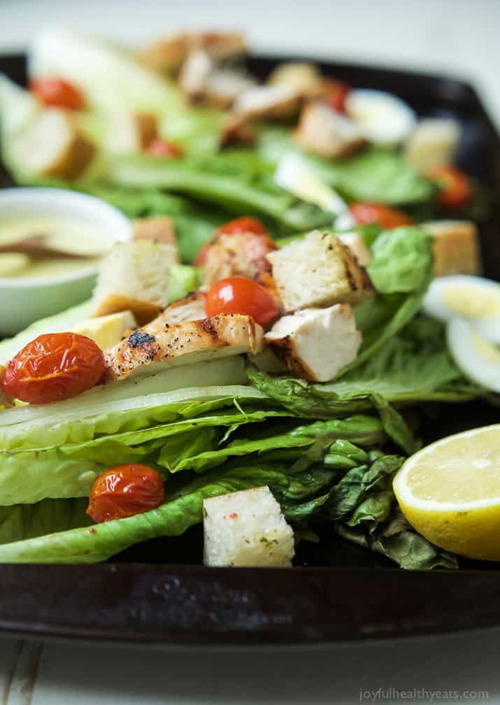 Close-up view of Grilled Chicken Caesar Salad on whole romaine leaves with grape tomatoes 