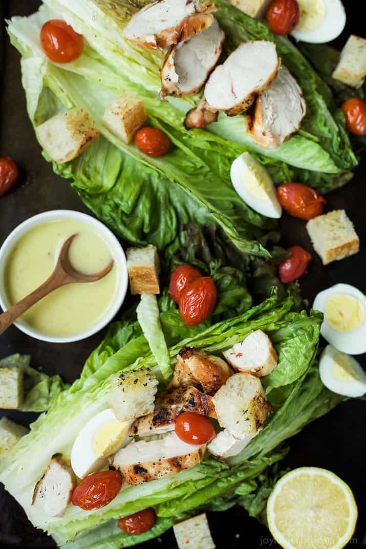 Top view of Grilled Chicken Caesar Salad on whole romaine leaves with grape tomatoes and hard-boiled eggs