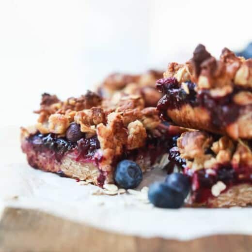 Homemade lemon blueberry bars stacked on top of each other on top of a cutting board