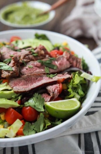 An easy healthy Southwestern Steak Salad loaded with vegetables, tender Ribeye Steak and then topped with a homemade Cilantro Avocado Dressing! Done in 15 minutes, low on calories and rivals any restaurant salad! | joyfulhealthyeats.com #glutenfree