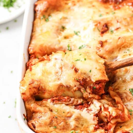 Cheesy lasagna rolls with marinara sauce in the baking dish.