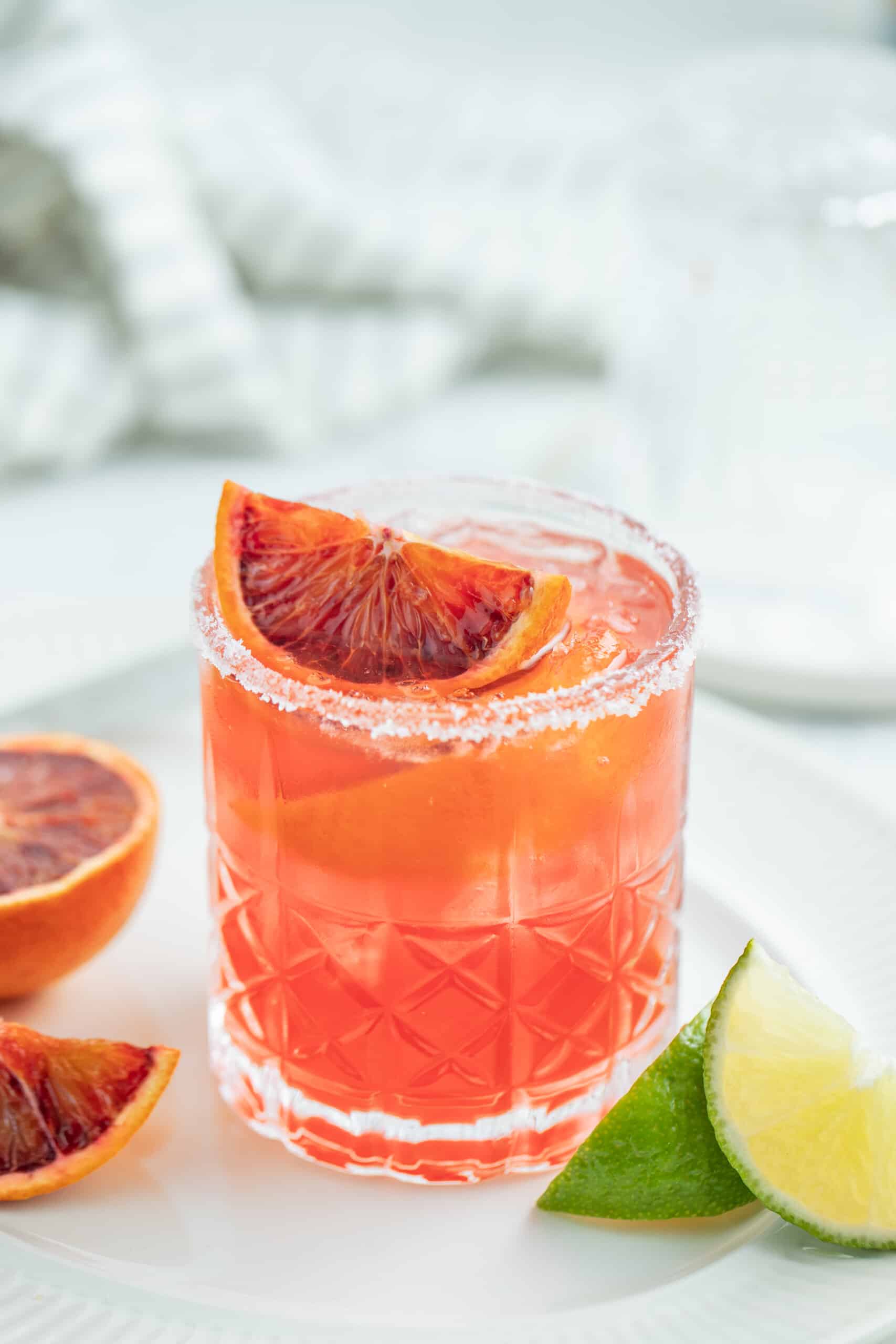 This Fresh Blood Orange Margarita Recipe is festive, citrusy, and flavorful. Plus, it's easy to make and doesn't include simple syrup! an ruby red colored margarita with blood orange garnish