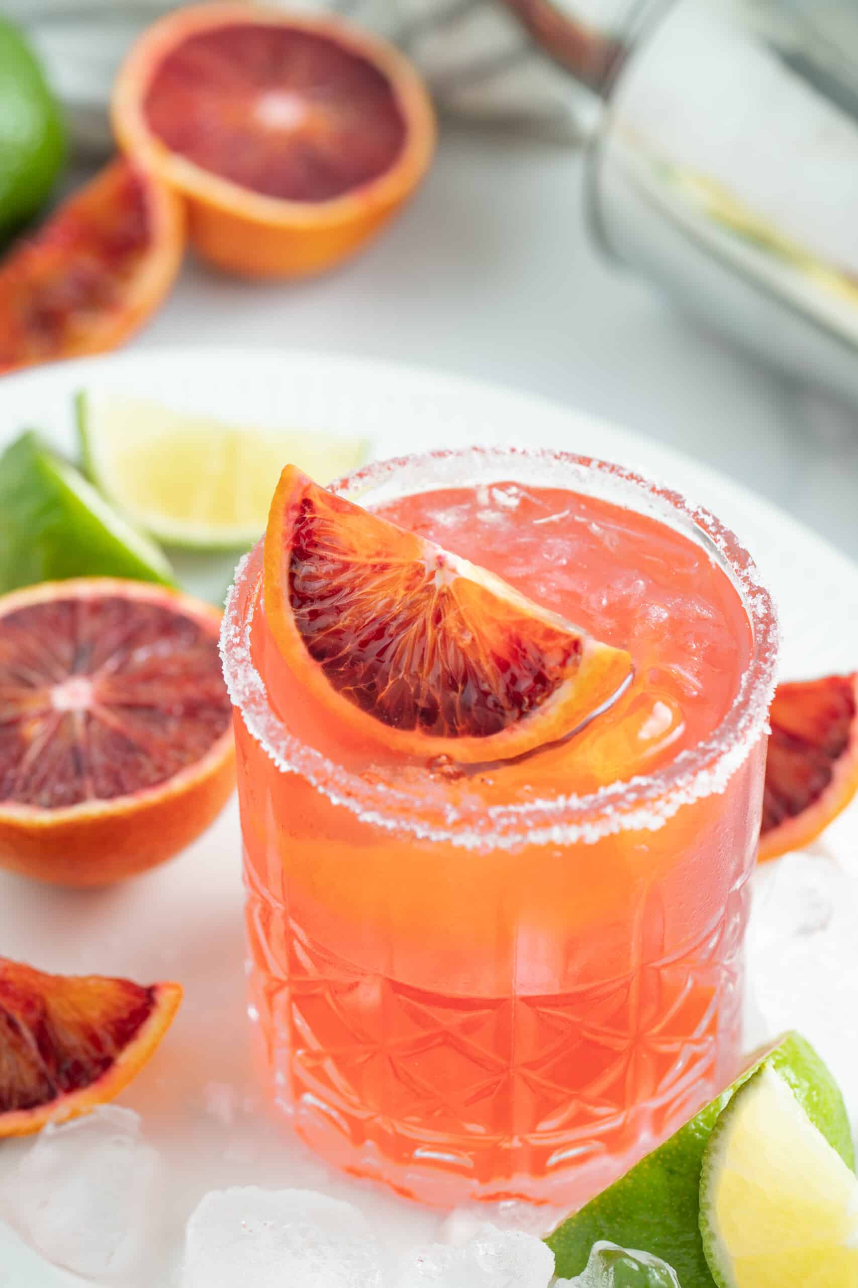 This Fresh Blood Orange Margarita Recipe is festive, citrusy, and flavorful. Plus, it's easy to make and doesn't include simple syrup! It's a wonderful margarita to serve during the holidays with it's deep red hue and big orange flavor. an ruby red colored margarita with blood orange garnish