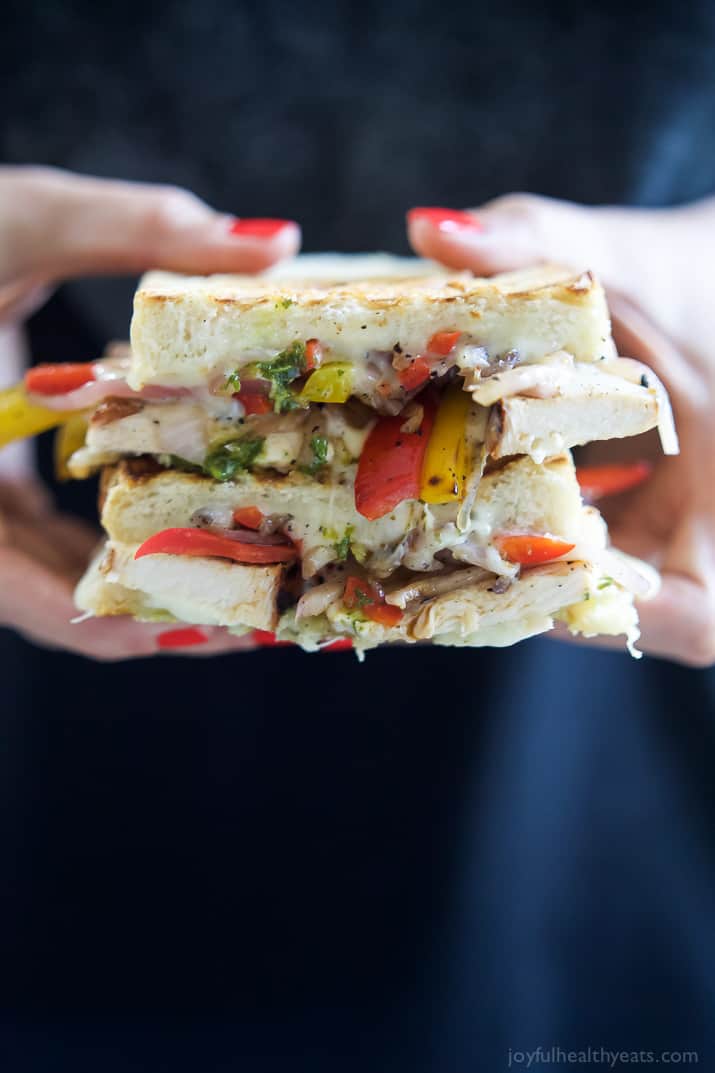 A person holding two halves of Grilled Chicken Fajita Panini stacked together