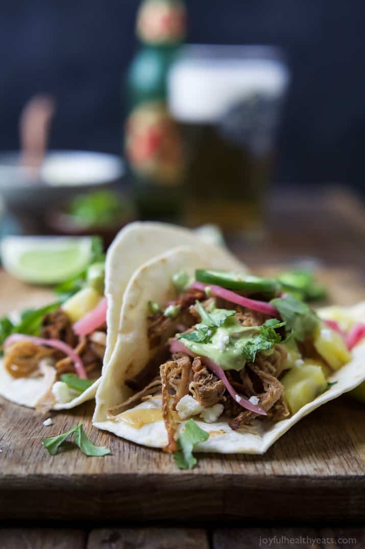 Crock Pot Pork Carnitas Tacos - the easiest pork carnitas you'll ever make with the BEST flavor from a secret ingredient. Then these tacos are topped with a creamy Cilantro Lime Avocado Crema for the ultimate bite! | joyfulhealthyeats.com