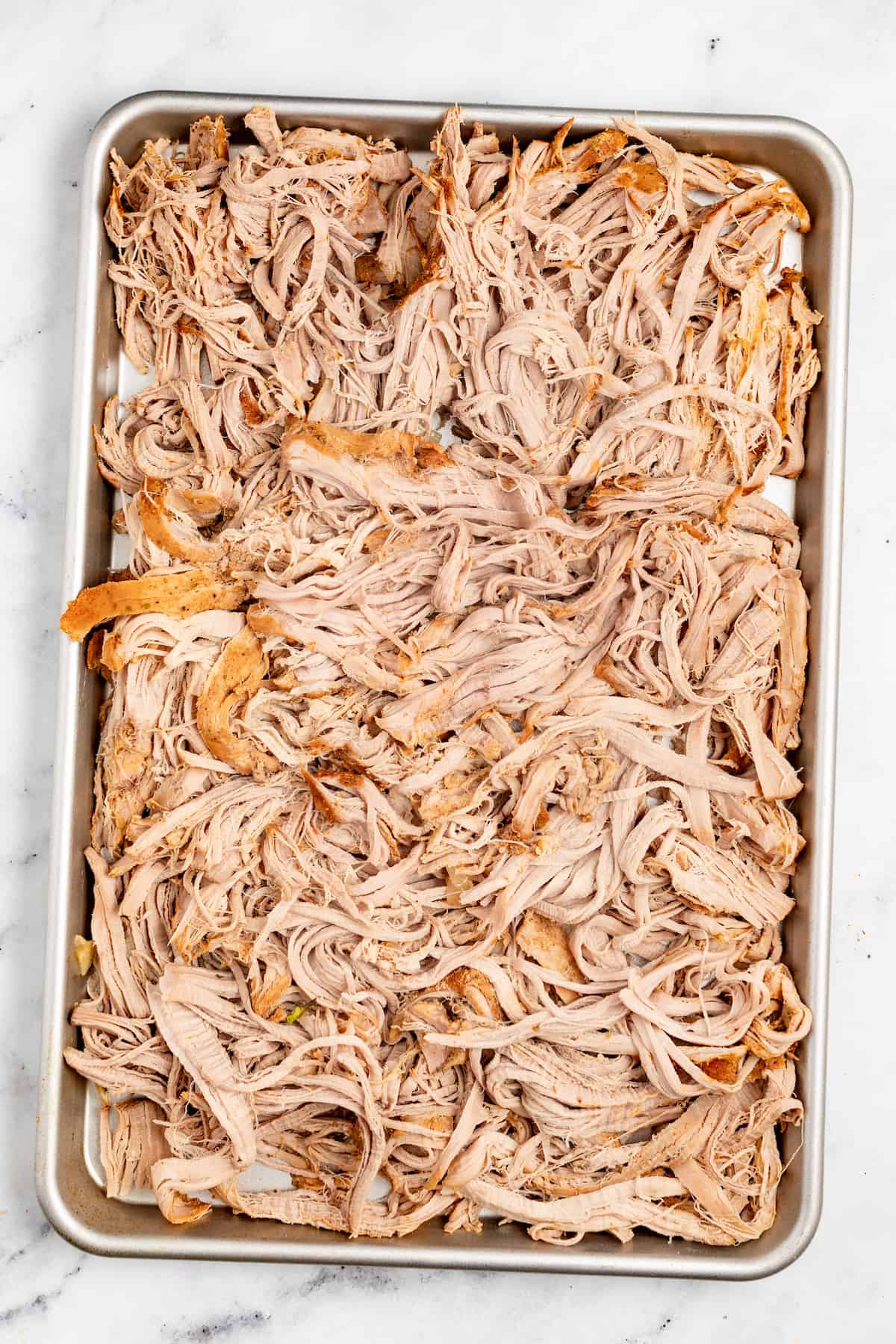 Shredded pork on the baking sheet before broiling. 