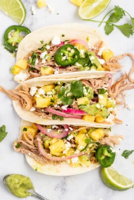 Three pork carnitas tacos with toppings.