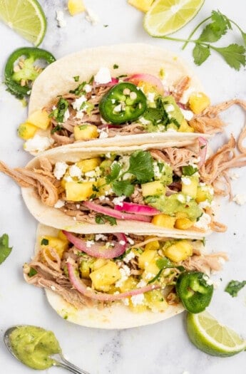 Three pork carnitas tacos with toppings.