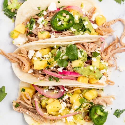 Three pork carnitas tacos with toppings.