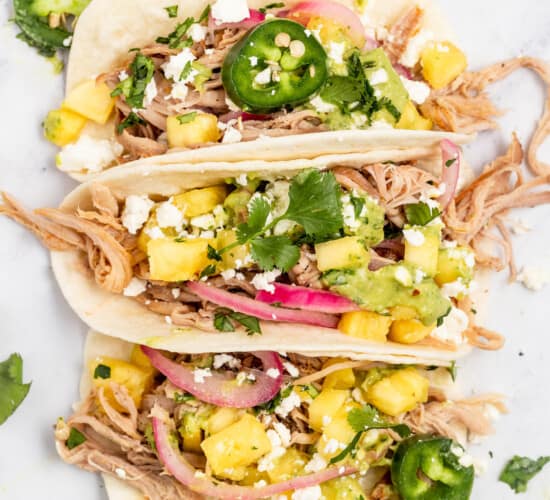 Three pork carnitas tacos with toppings.