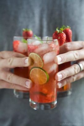 Three glasses of Strawberry Mojito being held by hands