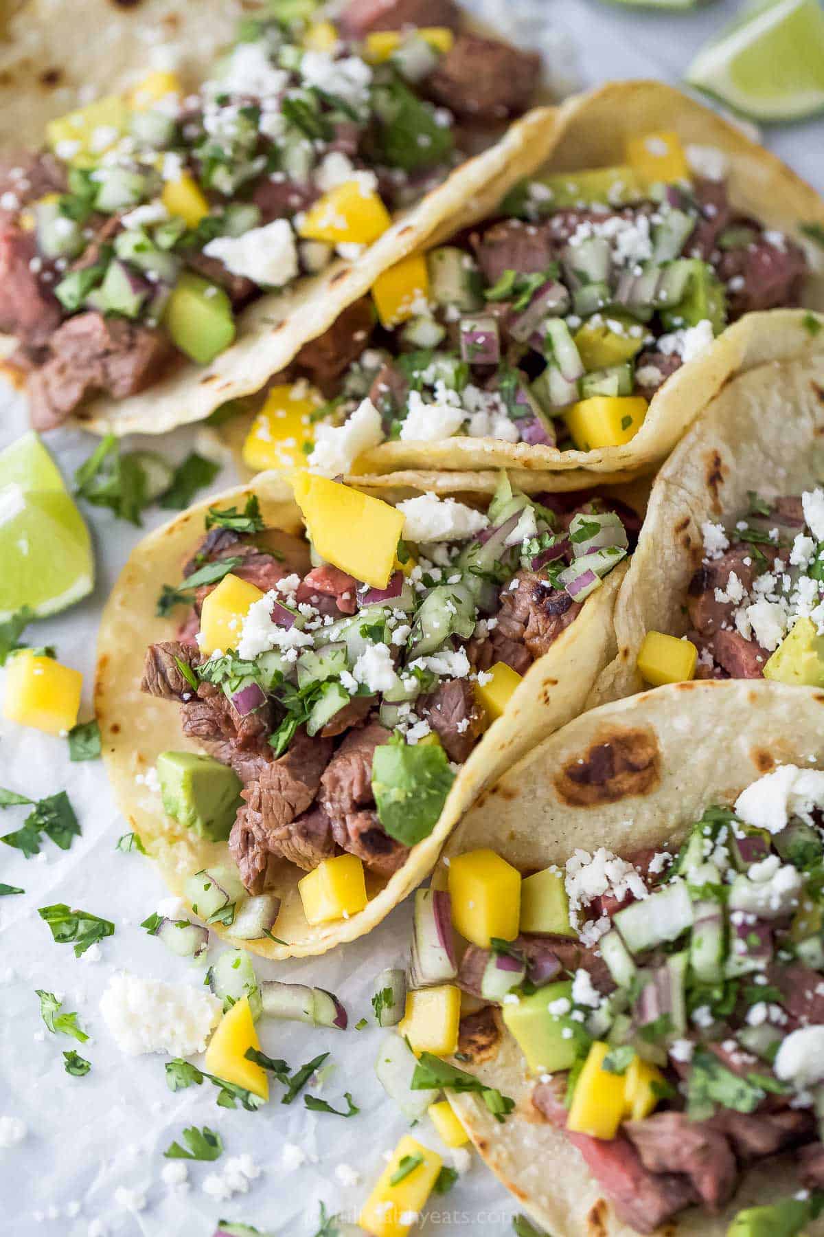 Three street tacos on a parchment-lined tray.
