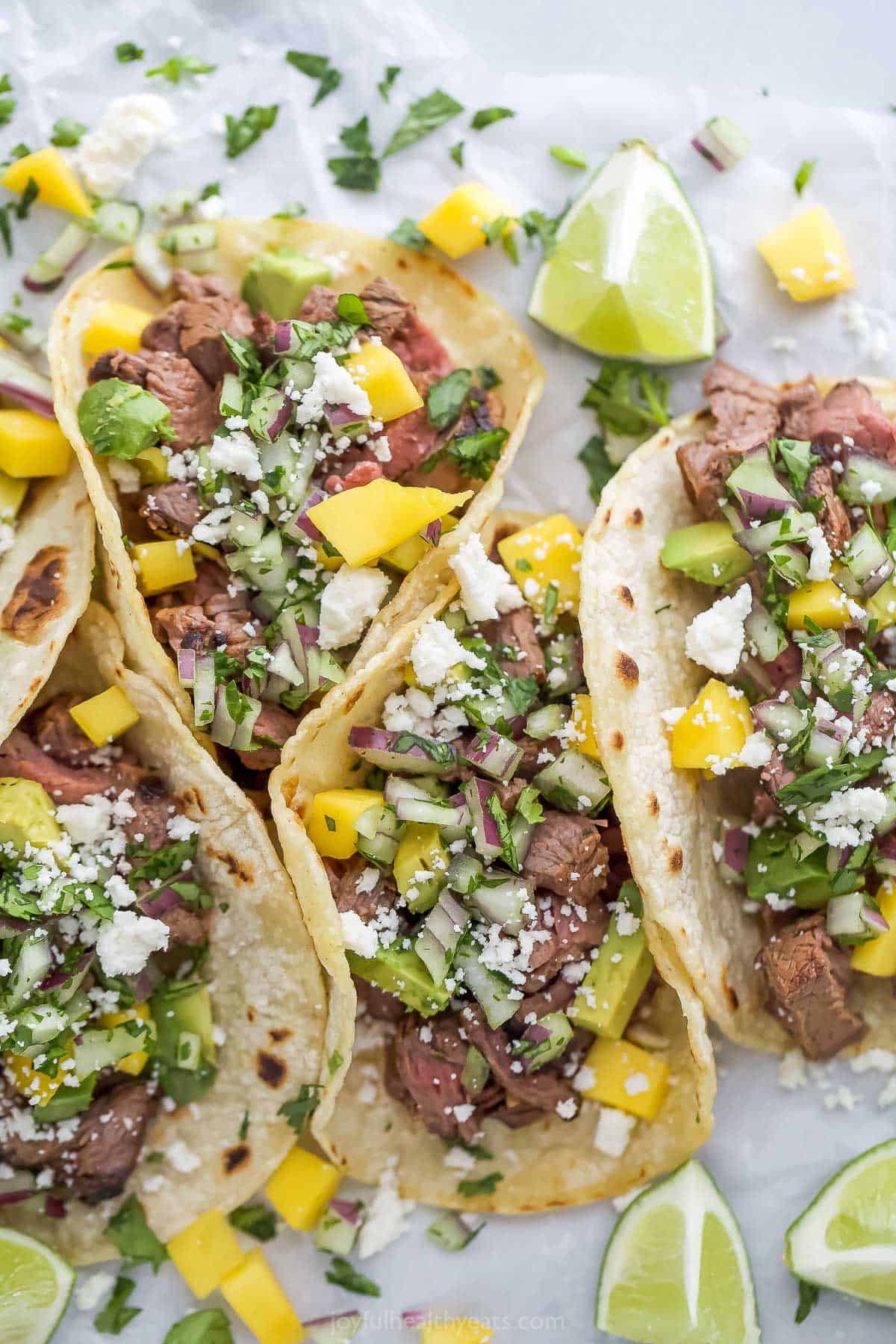 Street tacos with toppings and lime wedges on the side. 