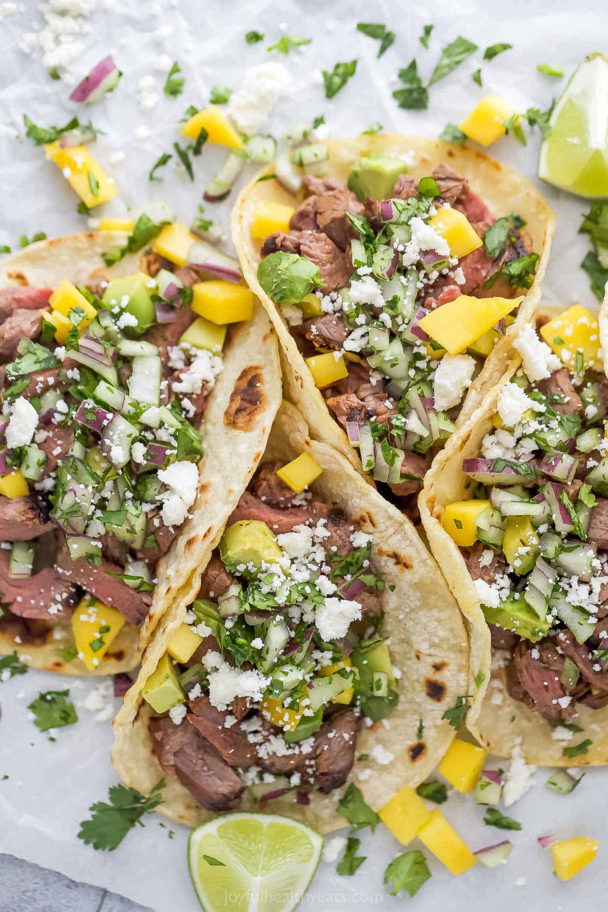 Overhead photo of four street tacos with toppings. 