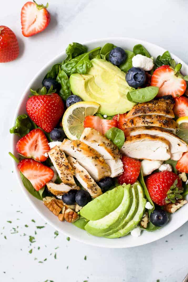 a bowl filled with best avocado strawberry salad with grilled chicken