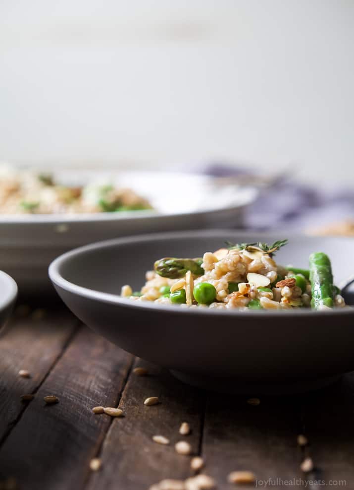 Side view of a bowl of Springtime Farro Salad with sweet peas, asparagus, fresh herbs and goat cheese