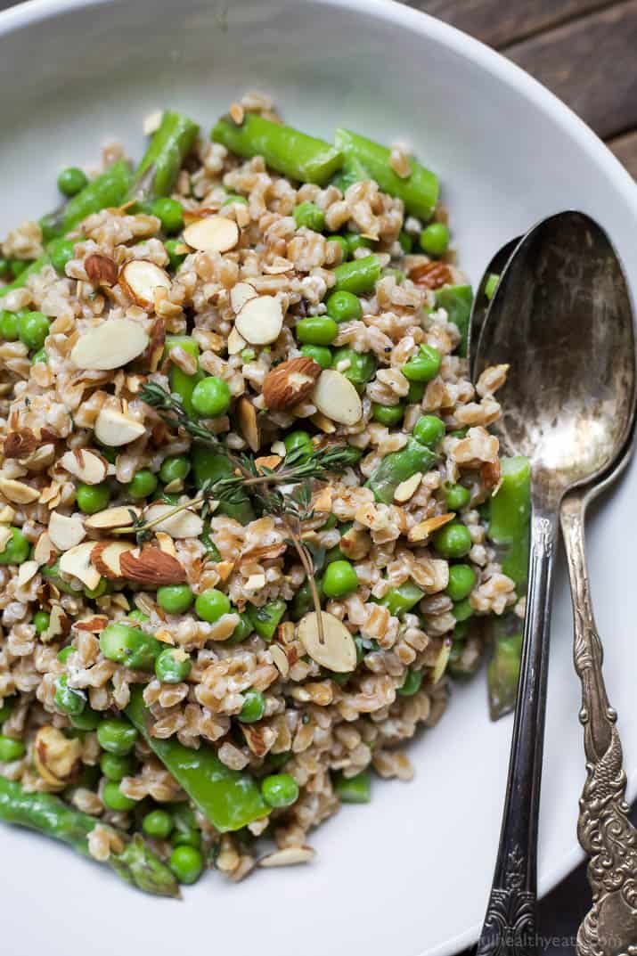 Top view of a bowl of Springtime Farro Salad with sweet peas, asparagus, fresh herbs and goat cheese