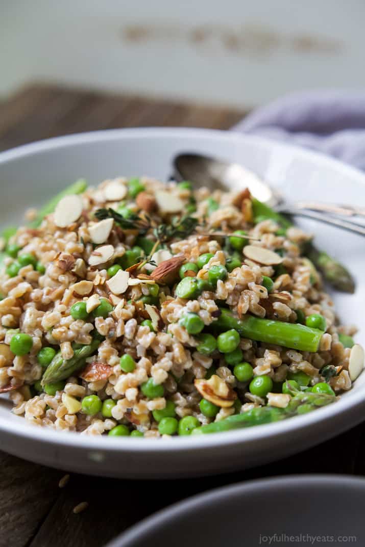 Springtime Farro Salad in a bowl with sweet peas, asparagus, fresh herbs and goat cheese