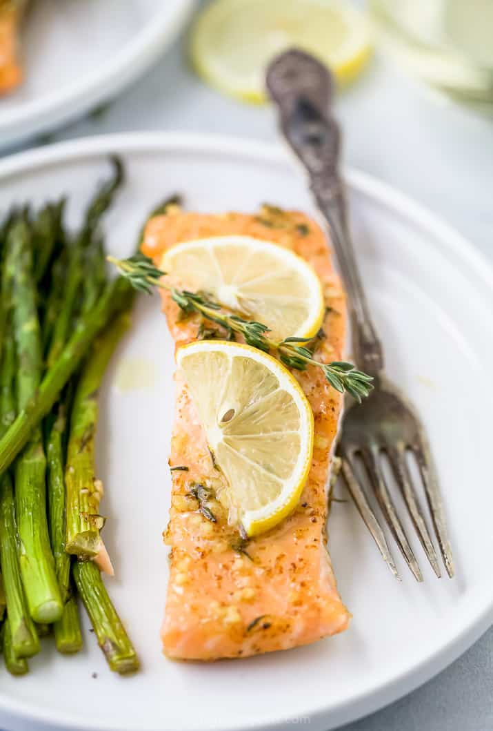 a plate with salmon topped with lemon and asparagus