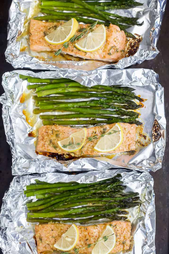 three tin foil packets with baked salmon and asparagus