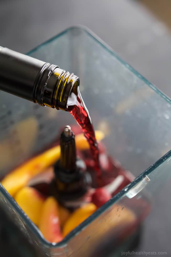 Red wine being added to fruit in a blender