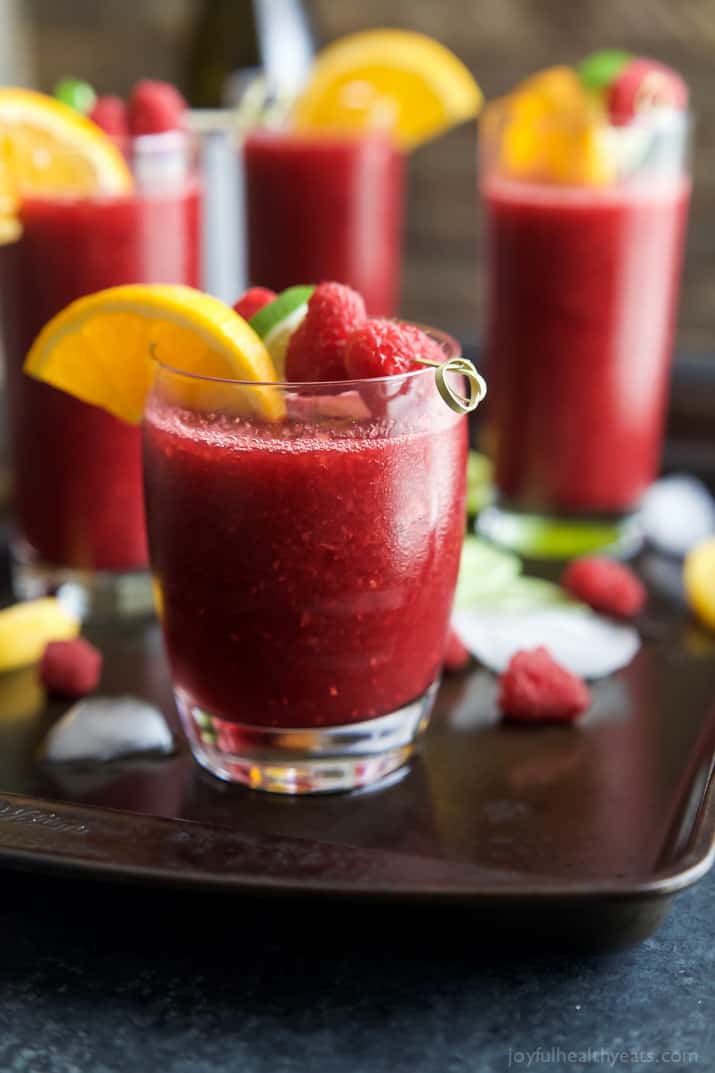 Glasses full of Frozen Raspberry Peach Sangria served with orange wedges and raspberries | joyfulhealthyeats.com