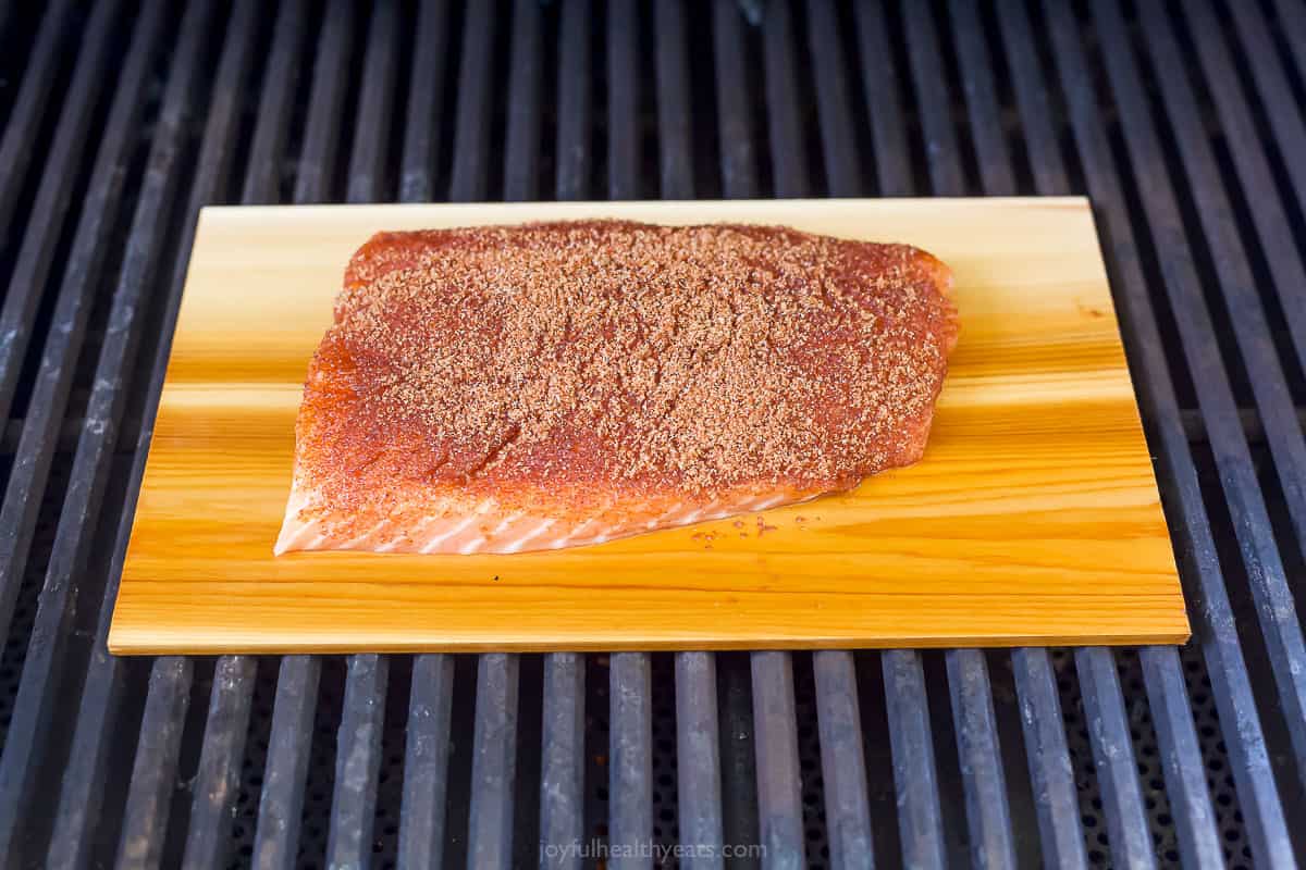 This 25-minute cedar plank salmon with strawberry salsa is flaky, spiced, smokey, and fruity all in one bite. It's perfect for the summer! Grilling the salmon on the cedar plank.