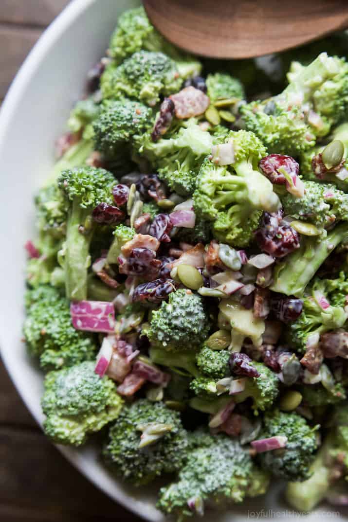 Lightened up Broccoli Salad filled with fresh broccoli, cranberries, red onion, pepitas, BACON, and creamy dressing made with greek yogurt! This salad will be a hit and you'll love the short cut I take! | joyfulhealthyeats.com #glutenfree