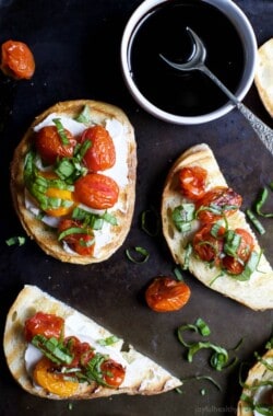 A table with pieces of Roasted Tomato Bruschetta with Whipped Goat Cheese and a bowl of balsamic reduction.