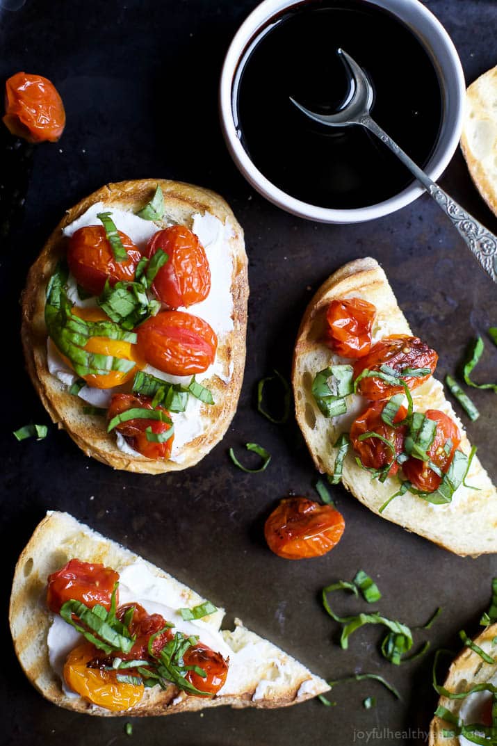 A table with pieces of Roasted Tomato Bruschetta with Whipped Goat Cheese and a bowl of balsamic reduction.