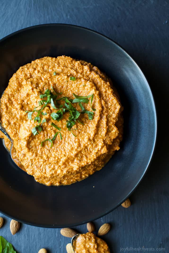 Top view of Romesco Sauce in a bowl topped with fresh herbs