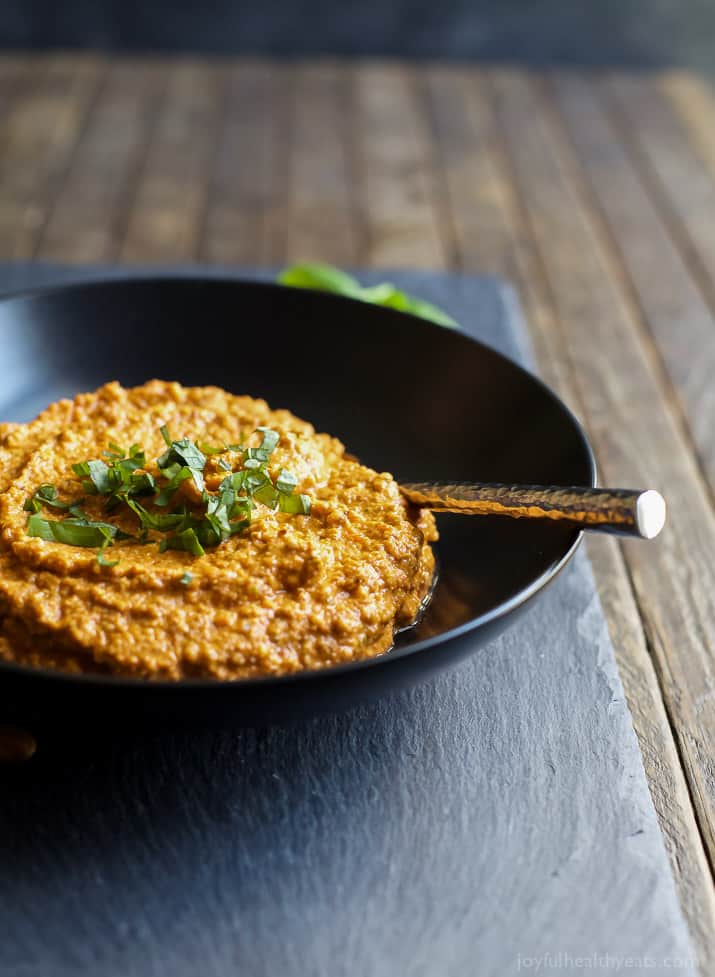 Romesco Sauce in a bowl topped with fresh herbs