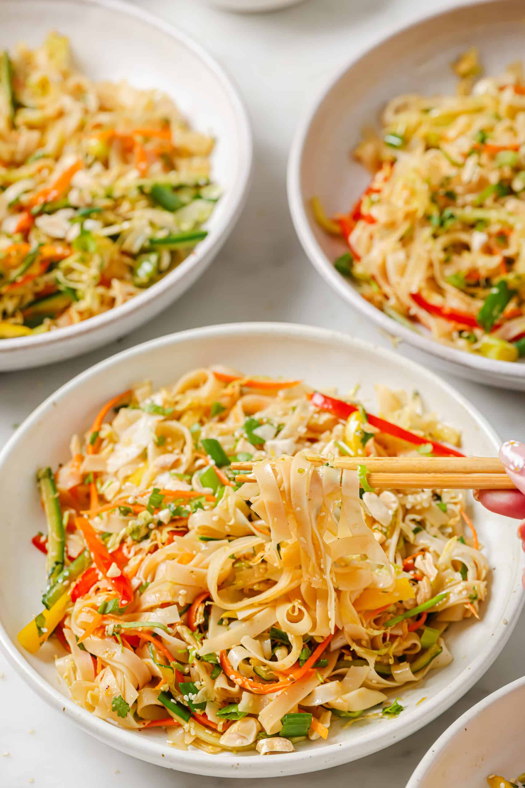 Three bowls of Asian noodle salad with sesame dressing.