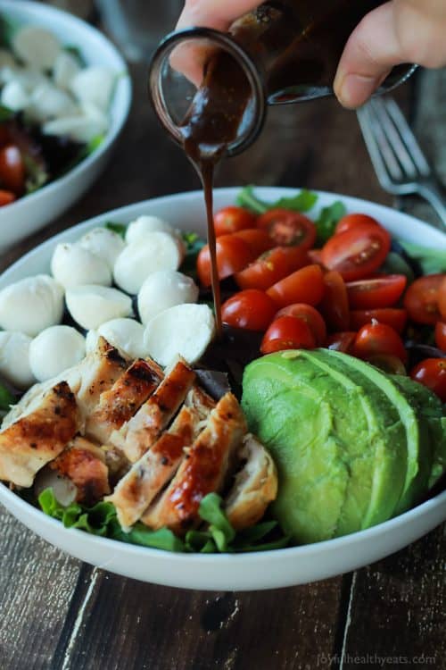 An Avocado Caprese Chicken Salad Being Topped with Balsamic Vinaigrette