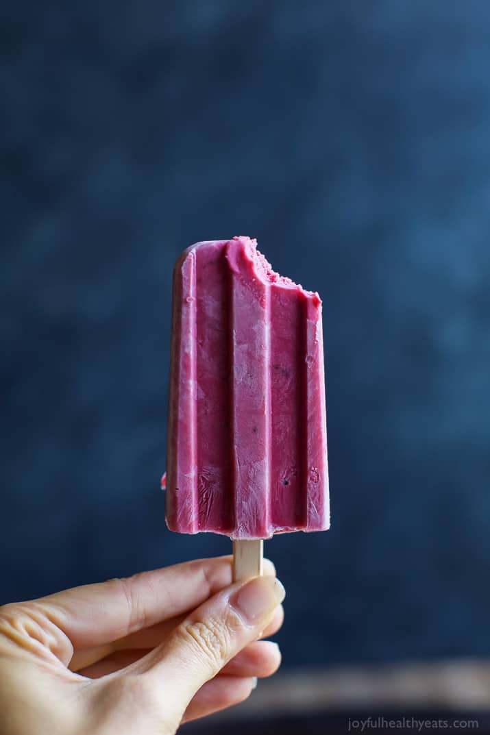 A Blackberry Thyme Yogurt Popsicle with a bite out of it