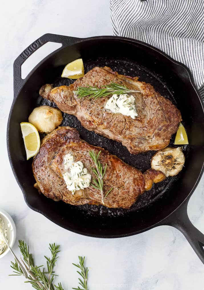 ribeye in a cast iron skillet with herb butter on top