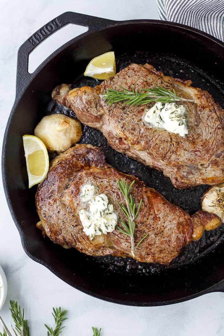 ribeye in skillet with butter herbs and lemon