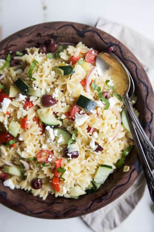 Simple Greek Pasta Salad with cherry tomatoes, artichokes, olives, red onion, cucumber, feta and a homemade dressing! The perfect summer side dish to take to your next party – I guarantee it will be the first dish to go!