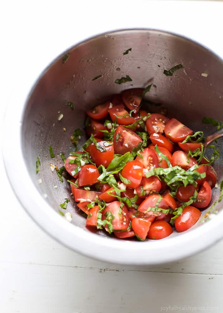 Diced grape tomatoes and fresh basil in a mixing bowl