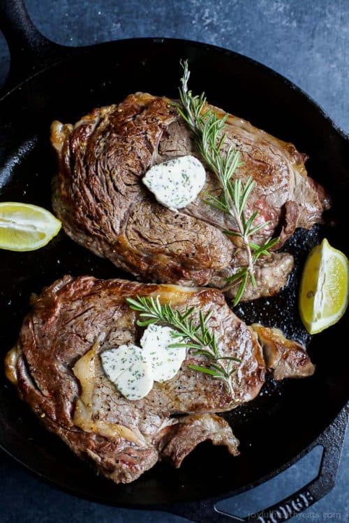 Two Pan-Seared Ribeye Steaks Cooking with Butter, Lemon and Rosemary