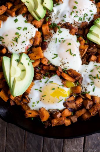A skillet full of Smoky Bacon Sweet Potato Hash with eggs, avocado, and bacon.