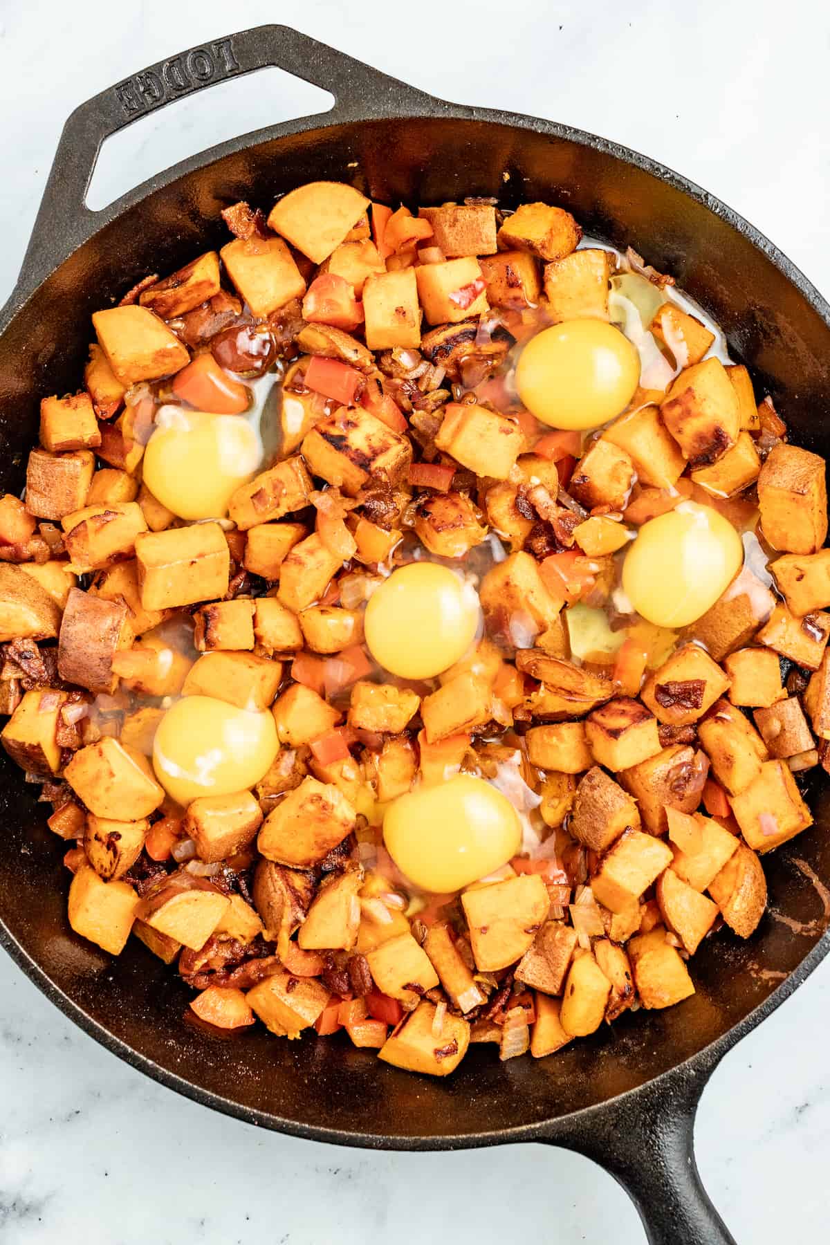 This sweet potato hash is packed paprika, crispy bacon, and eggs for the perfect sweet and savory breakfast bite. Adding the eggs to the skillet.