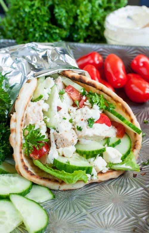 A Greek Chicken Gyro Pita Wrap Wrapped in Tinfoil on an Outdoor Table