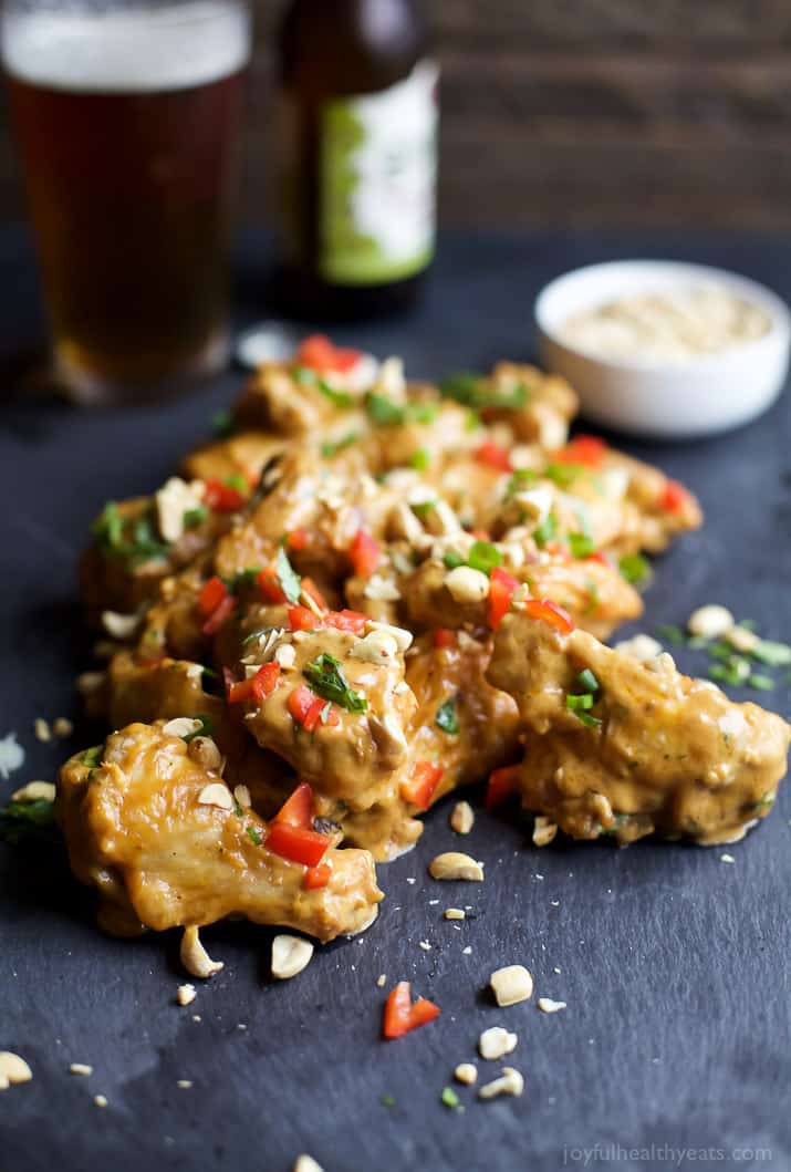 Baked chicken wings on a grey plate toss with peanut sauce