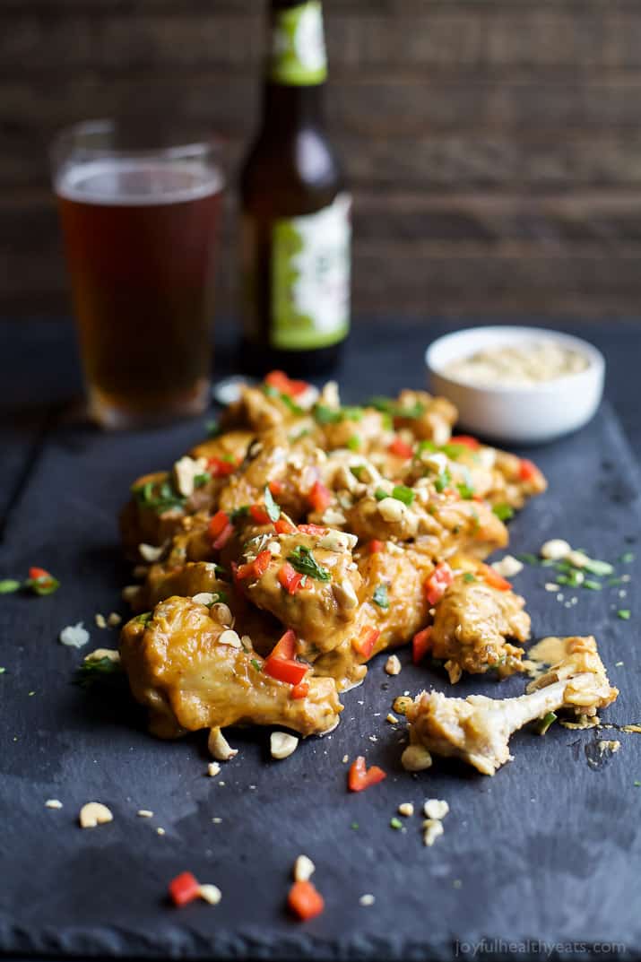 Baked chicken wings with peanut sauce on a table with a glass of beer