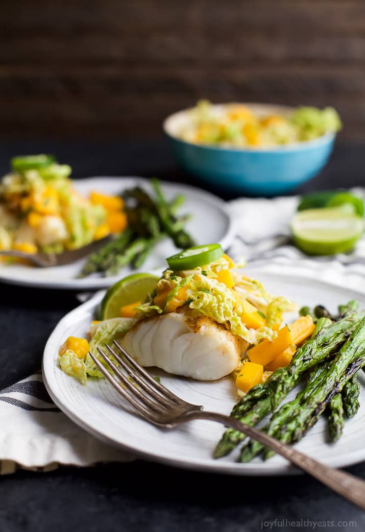 Grilled White Fish topped with Mango Jalapeno Coleslaw next to Asparagus on a plate