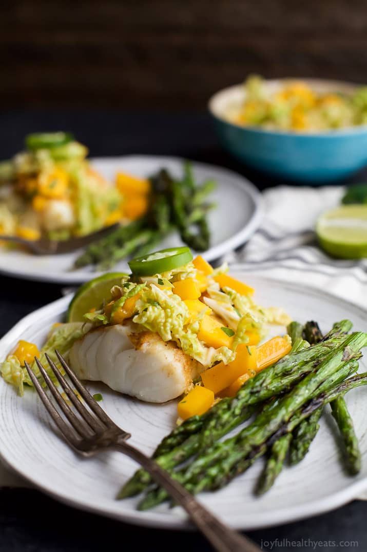 Grilled White Fish topped with Mango Jalapeno Coleslaw next to asparagus on a plate